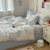 A light blue duvet cover set with white floral patterns and two matching pillows on a bed.
