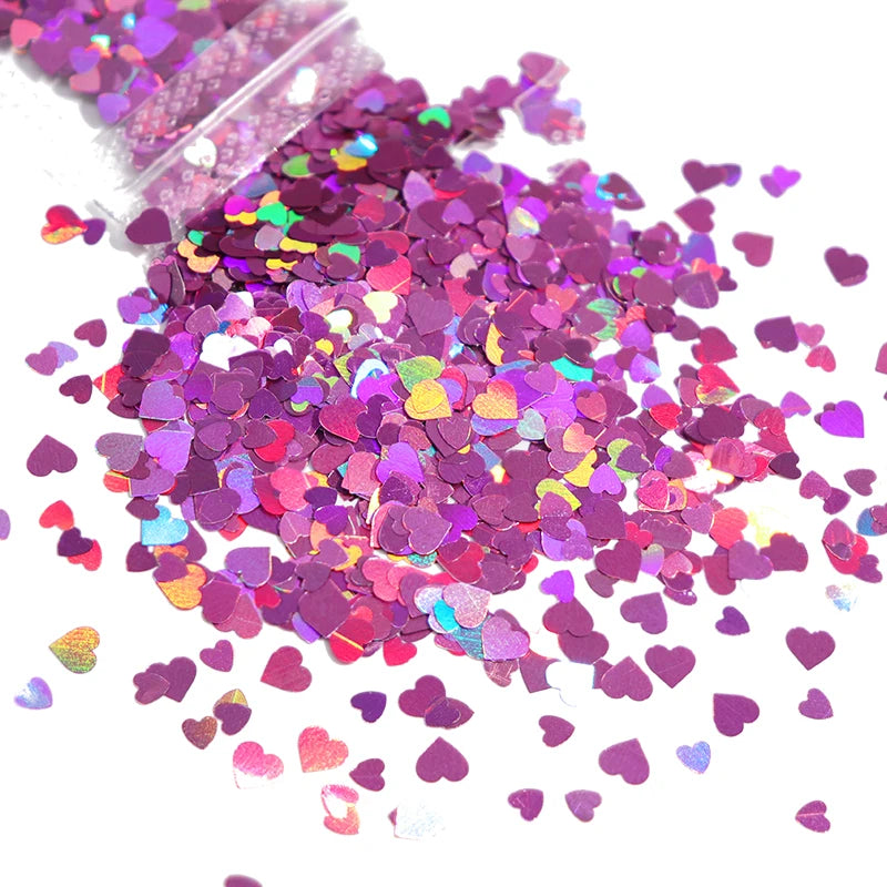 A pile of shiny holographic star sequins in various shades of purple and pink scattered on a white surface.