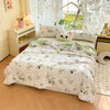 A white comforter with a panda print pattern and lace trim is displayed on a bed in a bright room.