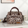 A brown and black leopard print insulated picnic lunch bag with a cross-body strap resting on a white surface.