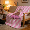 A pink and white striped throw blanket featuring a cartoon animal design draped over a wooden chair.