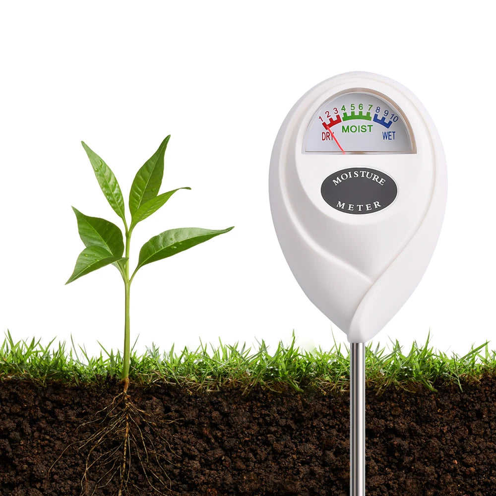 A white soil moisture meter with a metal probe inserted into dark soil next to a green plant.