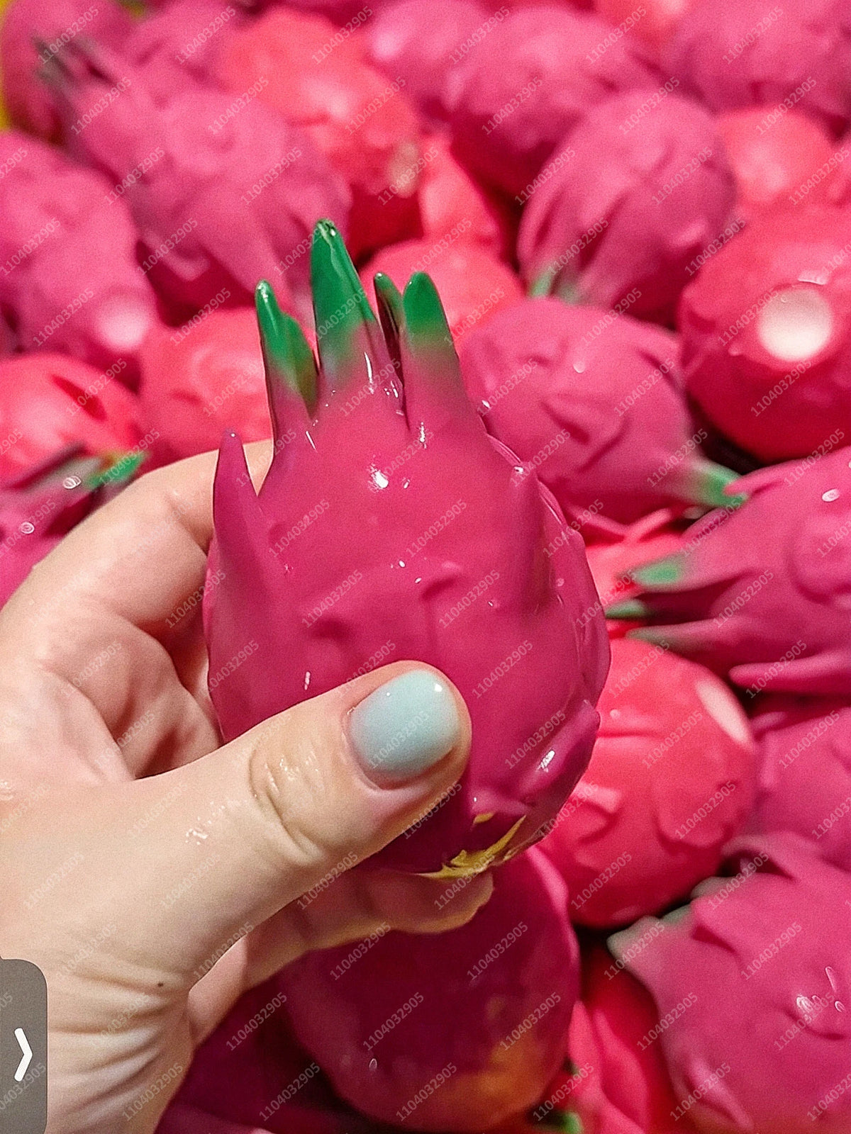 Eine Hand hält einen leuchtend pinken, strukturierten Kartoffel-Stressball mit vielen ähnlichen Artikeln umgeben.