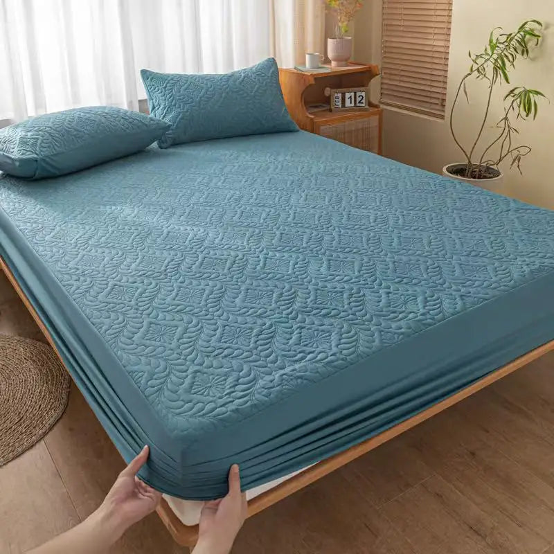 A teal quilted mattress protector with extra padding is displayed on a bed.