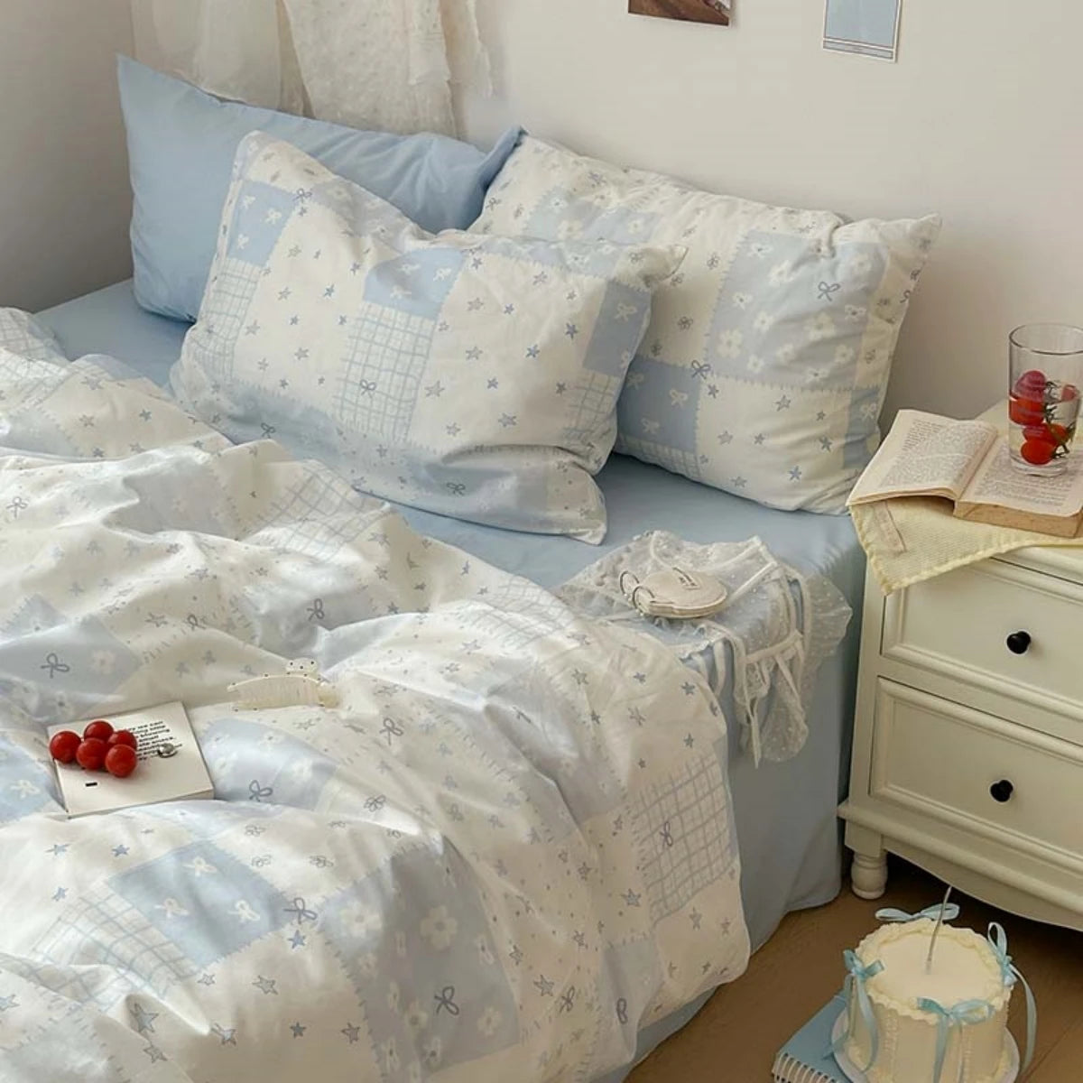 A light blue duvet cover set with white floral patterns and two matching pillowcases displayed on a bed.