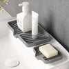 A white pump bottle and a bar of soap are placed on a gray silicone self-draining soap tray.
