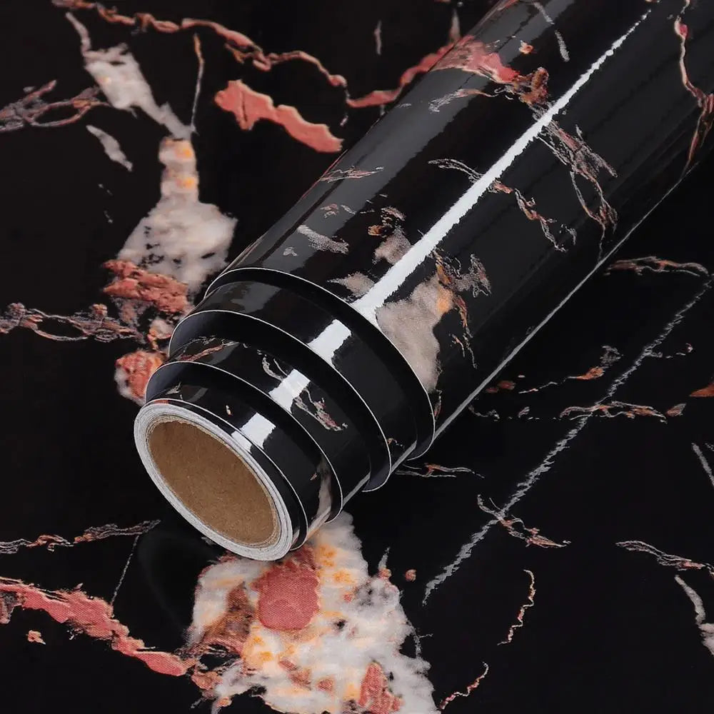Roll of black and pink marble wallpaper with white accents shown diagonally on a dark surface