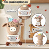 A handmade crochet Highland cow plush doll with a positive affirmation card and a wooden display stand.