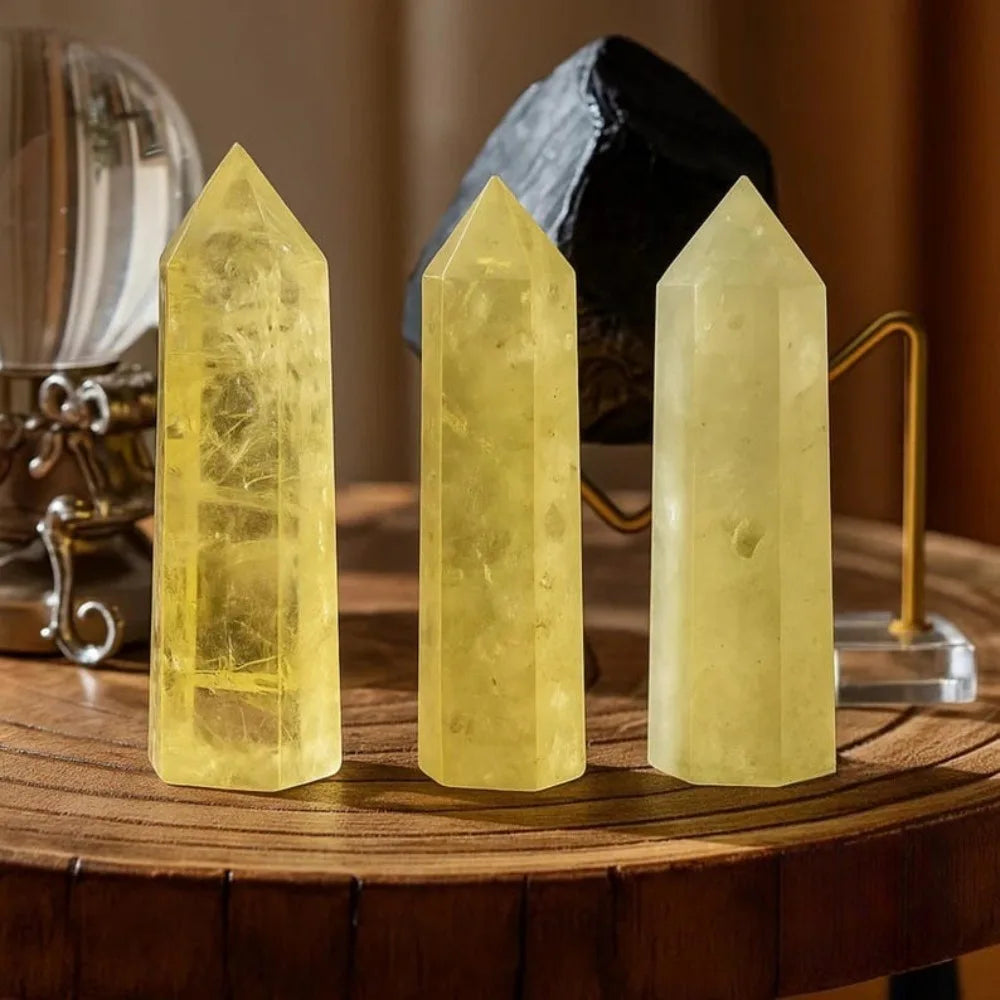 Three natural yellow citrine crystal towers displayed on a wooden surface.