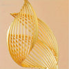 A close-up of a golden Nordic ceramic sculpture featuring vertical, flowing lines.