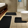 A set of black plush memory foam bath mats with non-slip backing placed on a tiled bathroom floor.