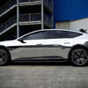 A silver sedan is shown in profile against a blue industrial background.