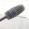 A silicone bottle brush with a long handle is shown cleaning the inside of a glass container.
