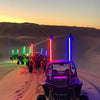 A vehicle is driving across a snowy landscape with several bright light bars mounted on the vehicle.