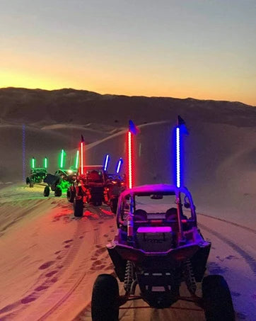 A vehicle is driving across a snowy landscape with several bright light bars mounted on the vehicle.