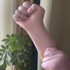 Nahaufnahme einer Hand mit pinker Einweg-Nitrile-Haube, geballt in einer Faust.