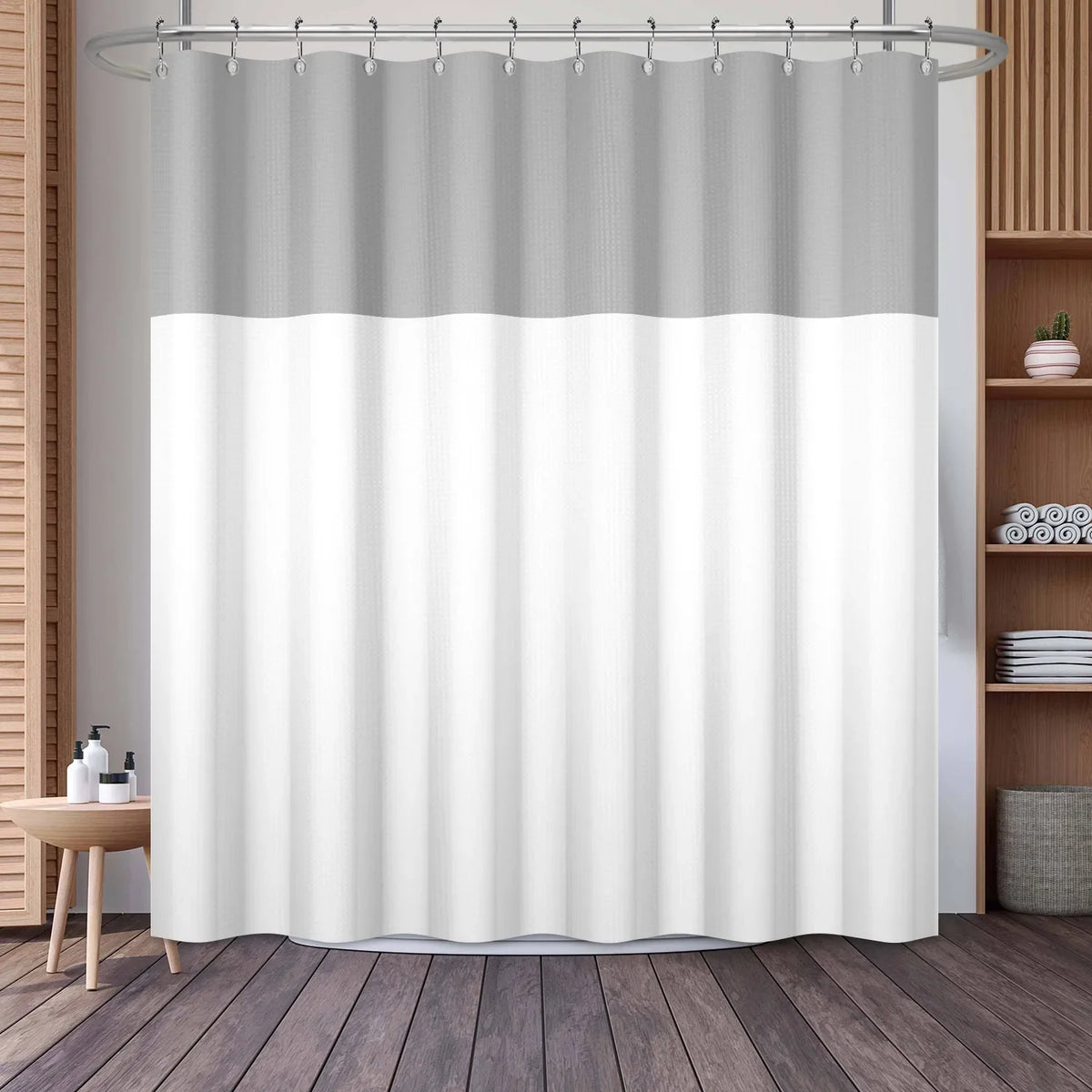 A white and gray waffle weave shower curtain with a geometric stripe pattern hanging from a metal rod.