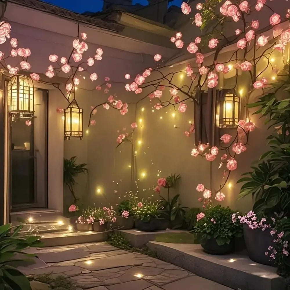 A garden scene featuring a cherry blossom tree with pink flowers illuminated by warm LED lights.