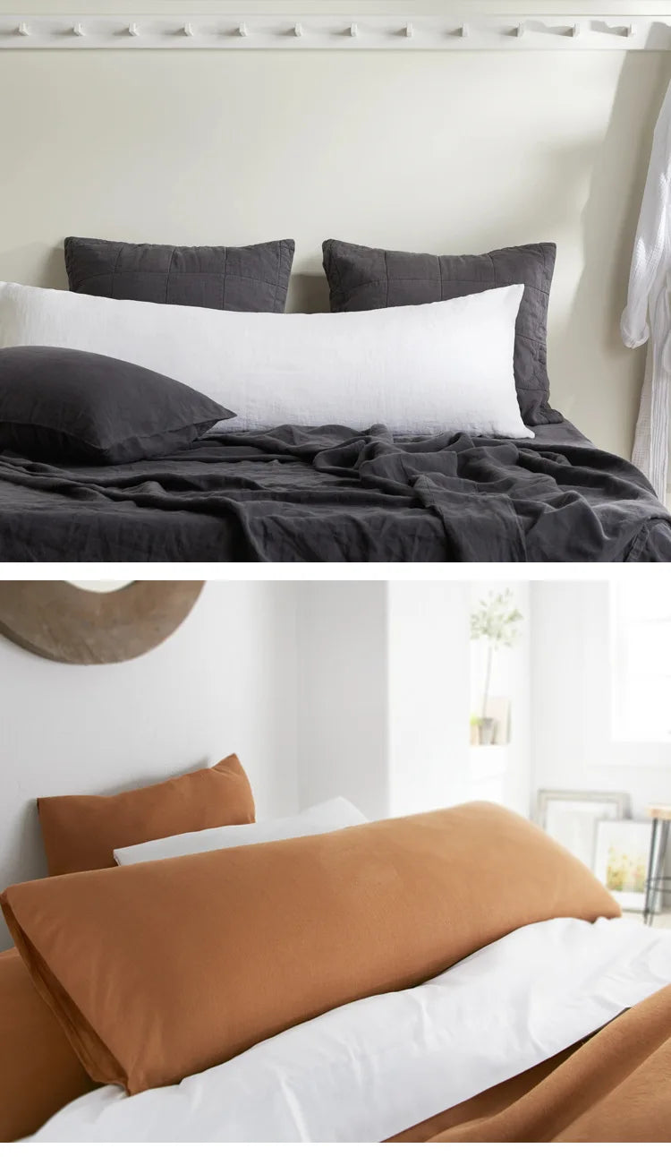 A close-up of a bed with dark gray and white linen pillows and bedding.