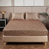 A bed dressed with luxury satin leopard print bedding set featuring brown and black animal print.