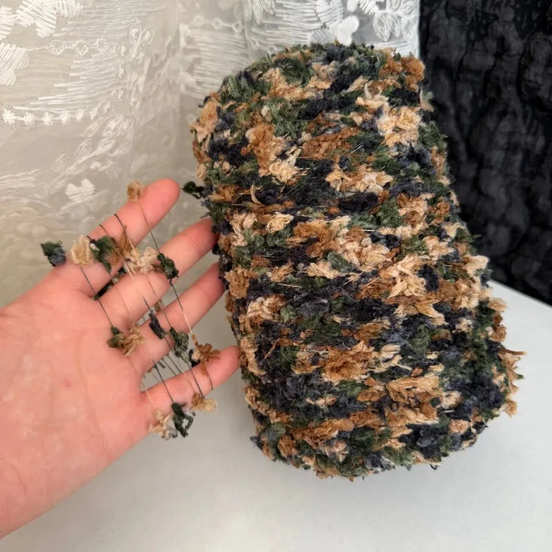 A hand holds a skein of hand-dyed variegated cotton blend yarn for knitting and crochet.