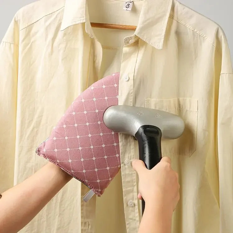A hand is using a portable handheld ironing board glove to iron a shirt.