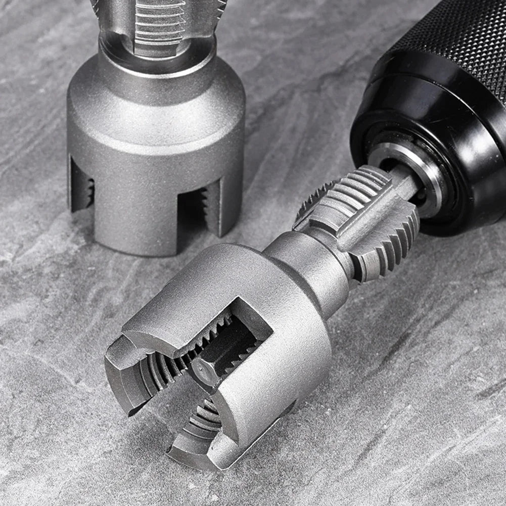 A close-up view of a metallic integrated pipe threading tool with a textured handle and cutting jaws resting on a gray stone 