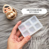 A hand holds a silicone paint palette tray with six wells on a gray furry background.