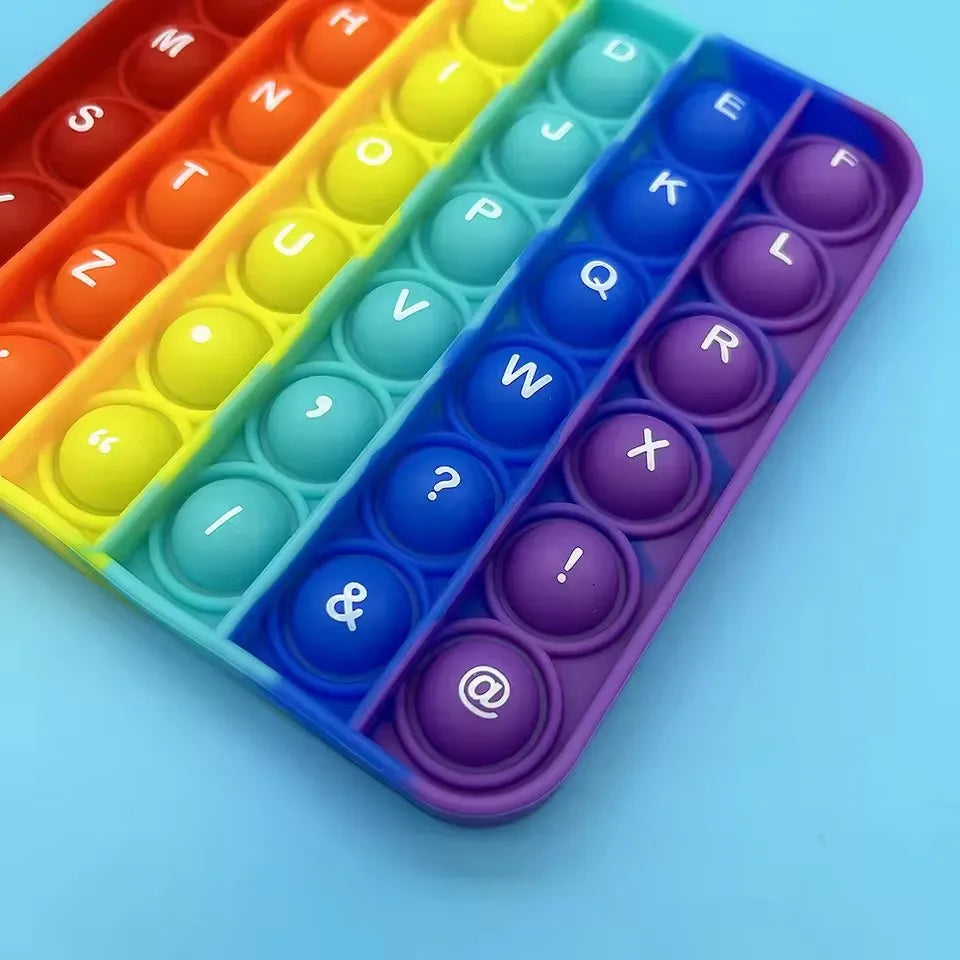 A colorful 2-in-1 alphabet and number fidget popper toy with various letter and number shapes arranged in compartments.