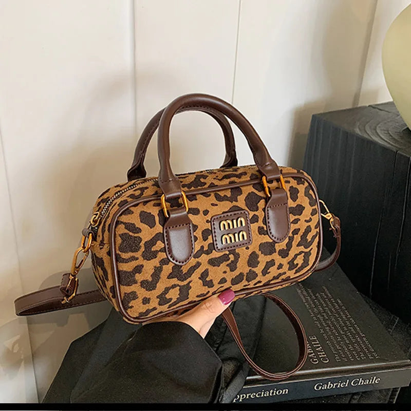 A brown retro leopard print hobo satchel bag with leather trim resting on a dark surface.