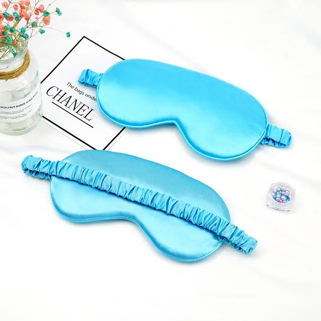 Light blue silk sleep mask with ruffled edges shown next to a packaged product.