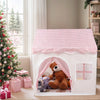 A white playhouse tent with a pink gingham roof and an arched entrance, decorated with stuffed animals.