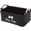 A black felt storage basket with wooden handles for organizing dog toys.