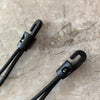 A close-up of a black heavy-duty elastic tie-down strap with metal hooks resting on a light marbled surface.