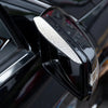 Close-up of a black car rearview mirror with a silver rain guard cover installed.