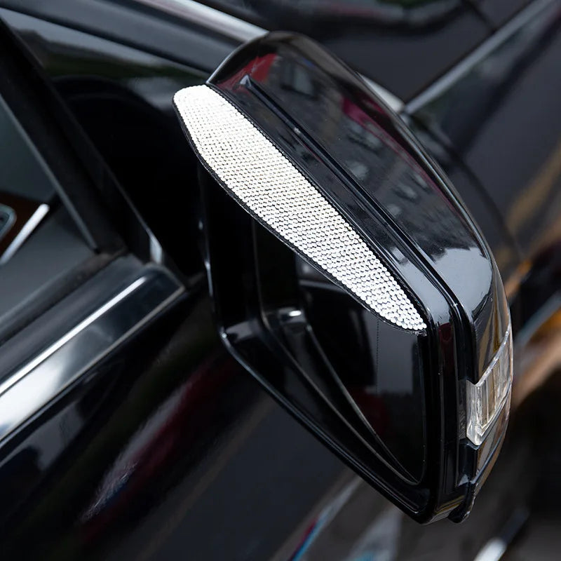 Close-up of a black car rearview mirror with a silver rain guard cover installed.