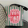 A pink and green striped tote bag featuring a red illustration of sardines.