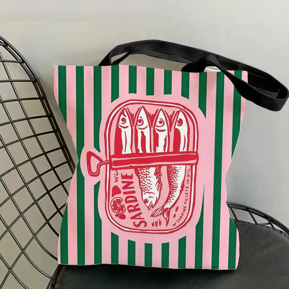 A pink and green striped tote bag featuring a red illustration of sardines.