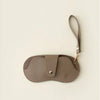 A brown PU leather glasses case with a retro lychee pattern and a thin strap.