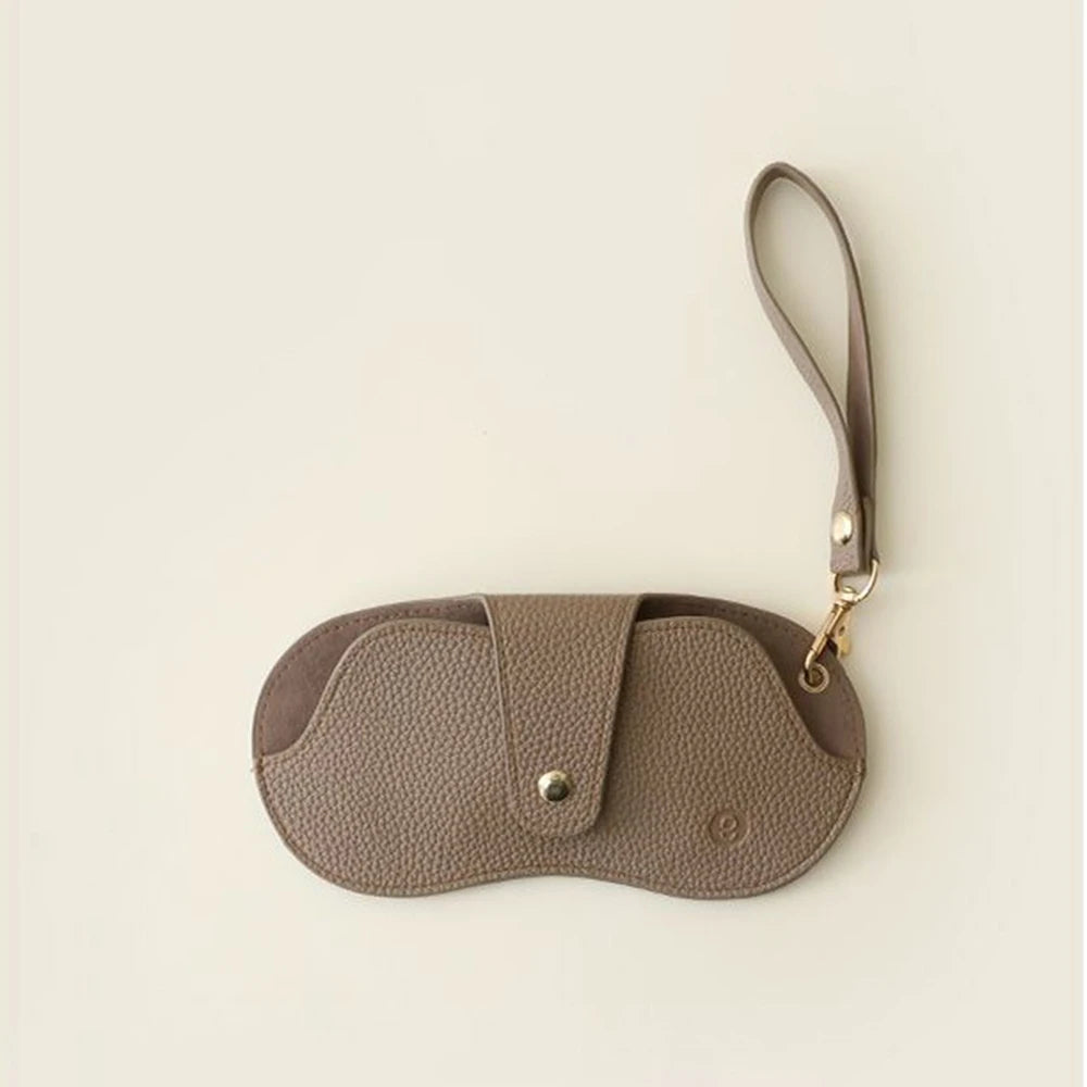 A brown PU leather glasses case with a retro lychee pattern and a thin strap.