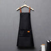 A black waterproof adjustable kitchen apron hanging on a wooden hanger.