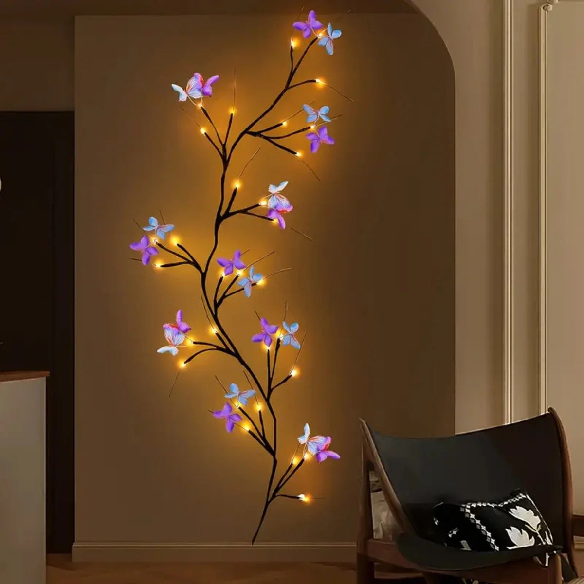 Guirlande lumineuse décorative en forme de vigne de saule avec des accents papillons lumineux sur un mur.