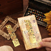 A hand holds a vintage metal bookmark with an artistic hollow design and gold tassel on a wooden surface.