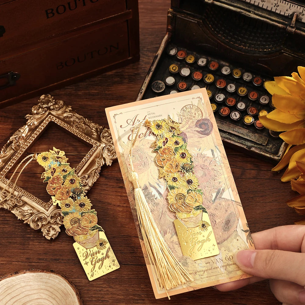 A hand holds a vintage metal bookmark with an artistic hollow design and gold tassel on a wooden surface.