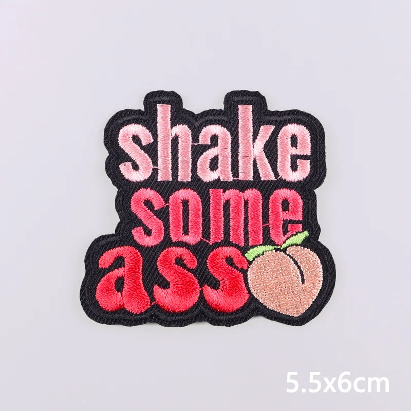Black embroidered patch with pink and red text that reads Shake some ass