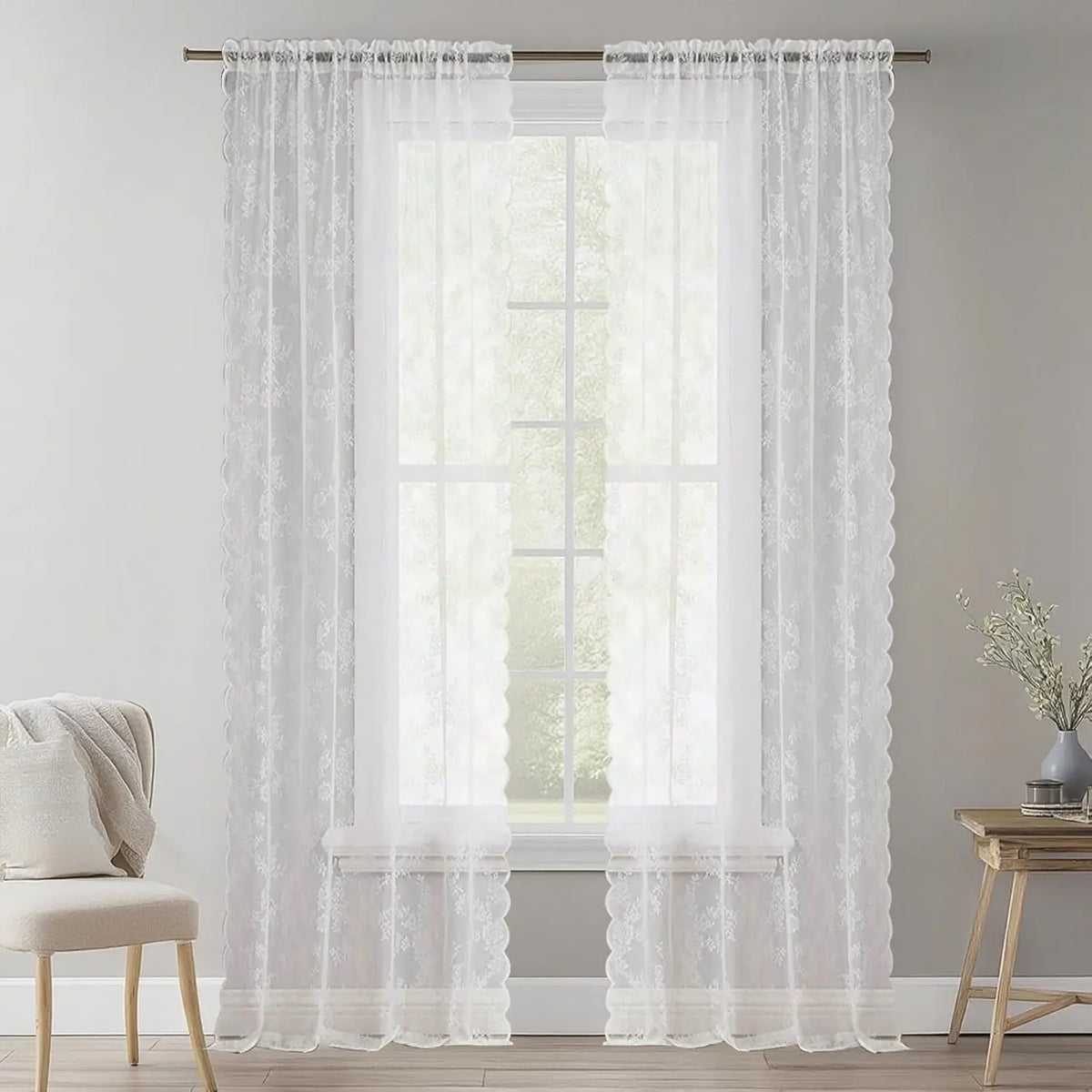 White vintage floral lace sheer curtains in two panels hanging over a window.