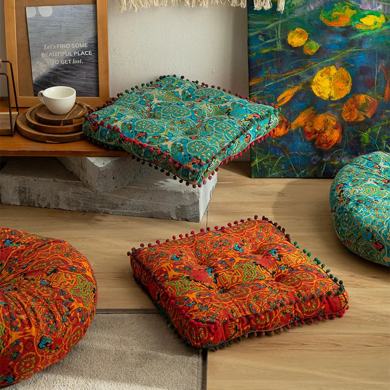 A collection of colorful bohemian cotton linen floor cushions and a large abstract painting on a wooden shelf.
