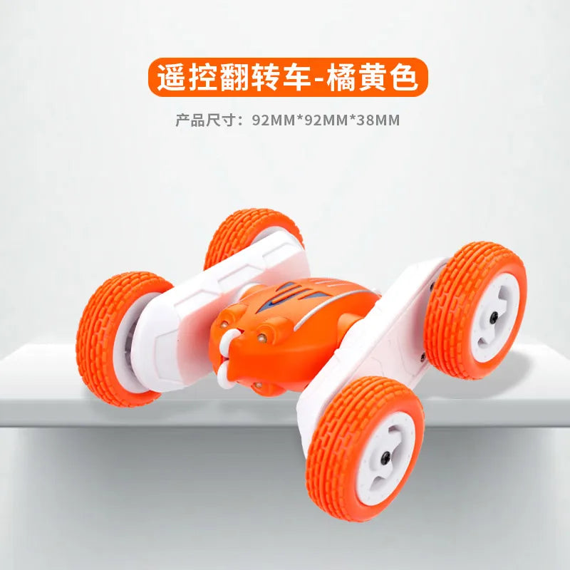 An orange and white remote control stunt car with four wheels is shown on a white surface.