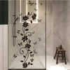 A vertical glass shower door featuring a black floral butterfly design on the surface.