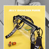 A clear jelly shoulder purse with a black strap and a lime slice, next to citrus fruit.